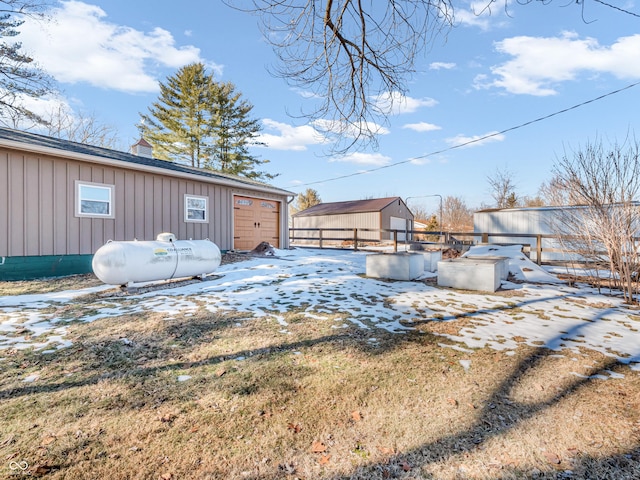 snowy yard with a garage and an outdoor structure