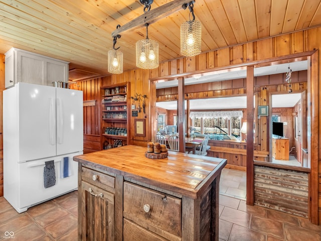 kitchen with a kitchen island, wood counters, wood walls, hanging light fixtures, and white fridge