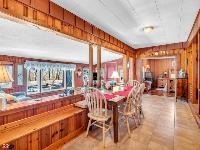 dining space featuring light tile patterned flooring and wooden walls