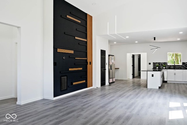 kitchen featuring a center island, white cabinets, light wood-type flooring, and decorative backsplash