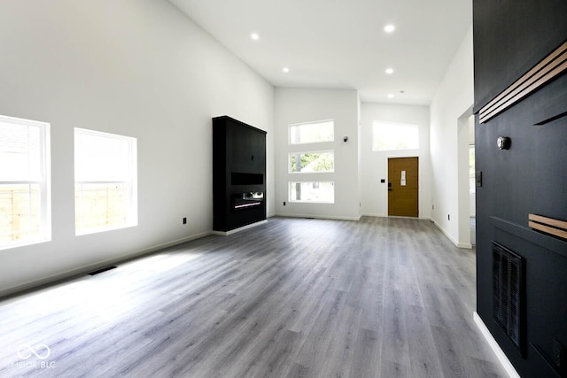 unfurnished living room with light wood-type flooring and a high ceiling