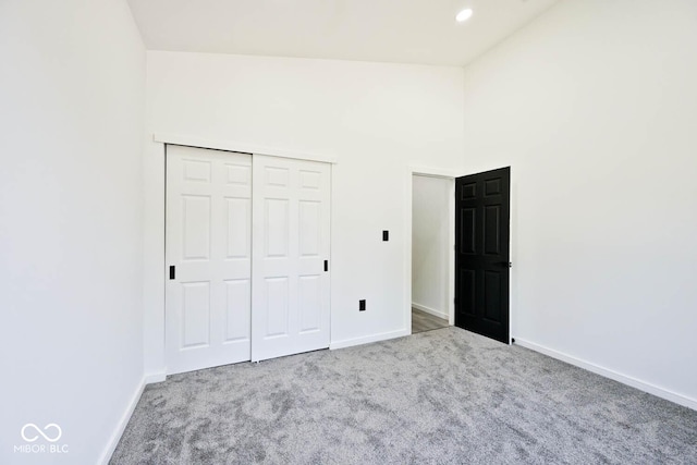 unfurnished bedroom featuring light colored carpet, a closet, and a towering ceiling