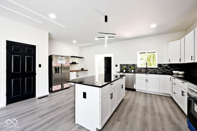 kitchen with white cabinetry, stainless steel appliances, a kitchen island, and light wood-type flooring