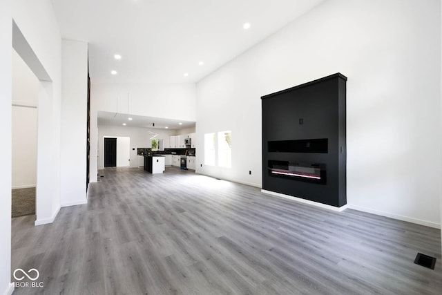 unfurnished living room featuring a towering ceiling and wood-type flooring