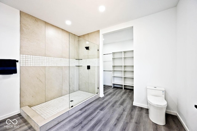 bathroom featuring tiled shower, toilet, and hardwood / wood-style floors