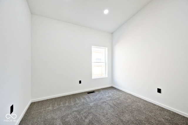 spare room featuring dark colored carpet