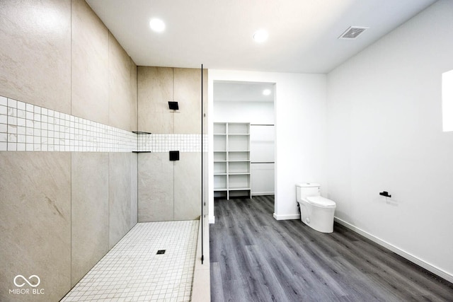 bathroom featuring hardwood / wood-style flooring, a shower, and toilet