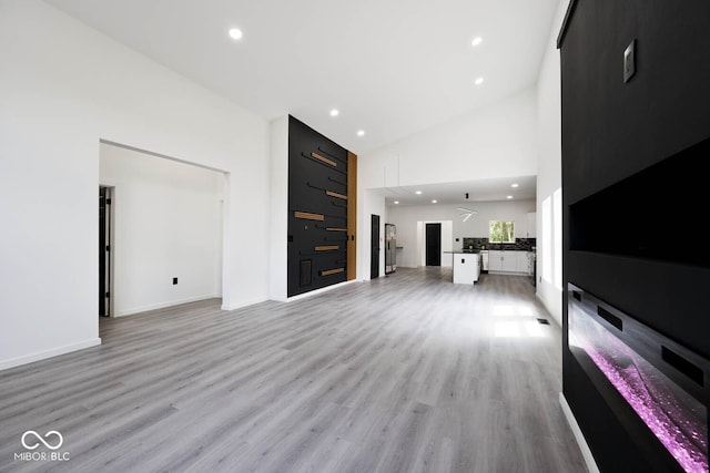 unfurnished living room with high vaulted ceiling and light hardwood / wood-style floors