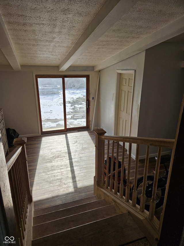 staircase with hardwood / wood-style flooring, a textured ceiling, and beam ceiling