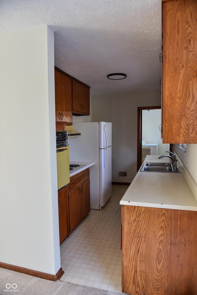 kitchen with sink, white appliances, and a textured ceiling