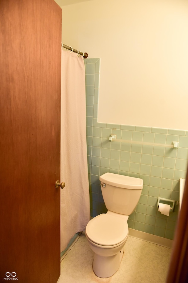 bathroom featuring tile walls, toilet, and walk in shower