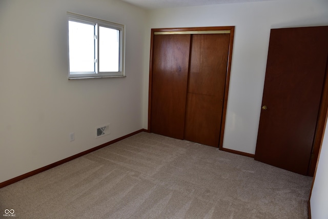 unfurnished bedroom with light colored carpet and a closet