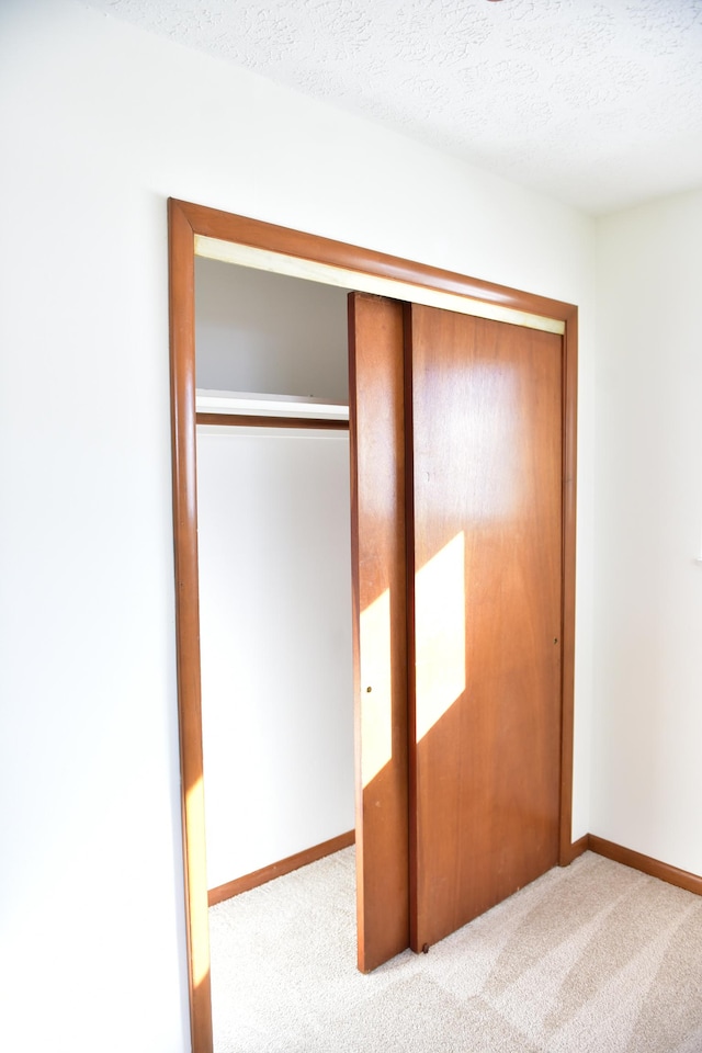 unfurnished bedroom featuring light carpet, a closet, and a textured ceiling