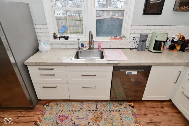 1719 Fletcher Ave, Indianapolis, IN 46203 - kitchen with sink, light hardwood / wood-style flooring, backsplash, black dishwasher, and white cabinets