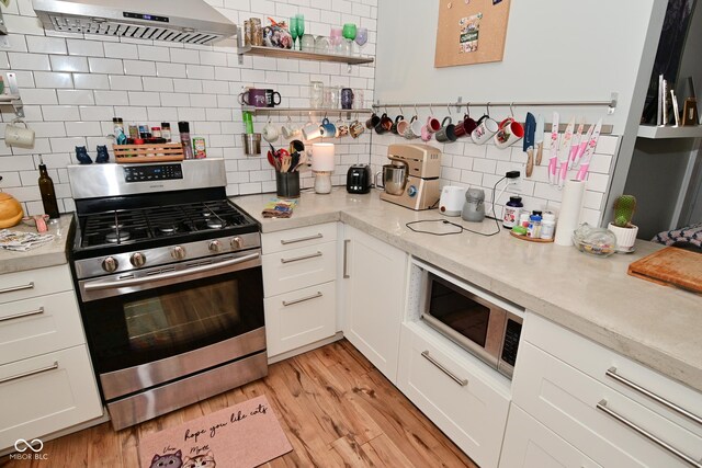 1719 Fletcher Ave, Indianapolis, IN 46203 - kitchen with range hood, light hardwood / wood-style floors, white cabinets, and appliances with stainless steel finishes