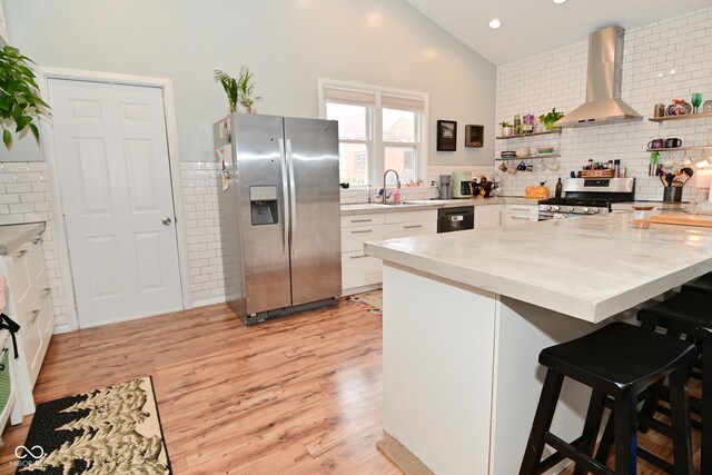 1719 Fletcher Ave, Indianapolis, IN 46203 - kitchen featuring a breakfast bar area, appliances with stainless steel finishes, white cabinets, kitchen peninsula, and wall chimney exhaust hood
