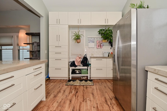 1719 Fletcher Ave, Indianapolis, IN 46203 - kitchen featuring white cabinetry, backsplash, stainless steel fridge, and light wood-type flooring