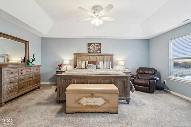 bedroom with light colored carpet, ceiling fan, and a tray ceiling