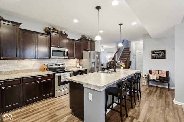 kitchen featuring decorative light fixtures, sink, a kitchen bar, a kitchen island with sink, and stainless steel appliances