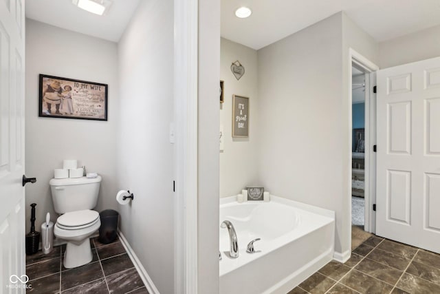 bathroom featuring tile patterned flooring, a tub to relax in, and toilet