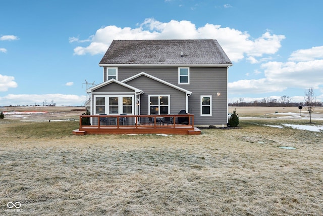 rear view of house featuring a rural view, a yard, a sunroom, and a deck