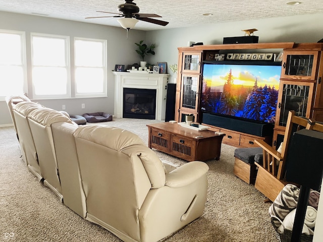 living room featuring ceiling fan, light carpet, and a textured ceiling