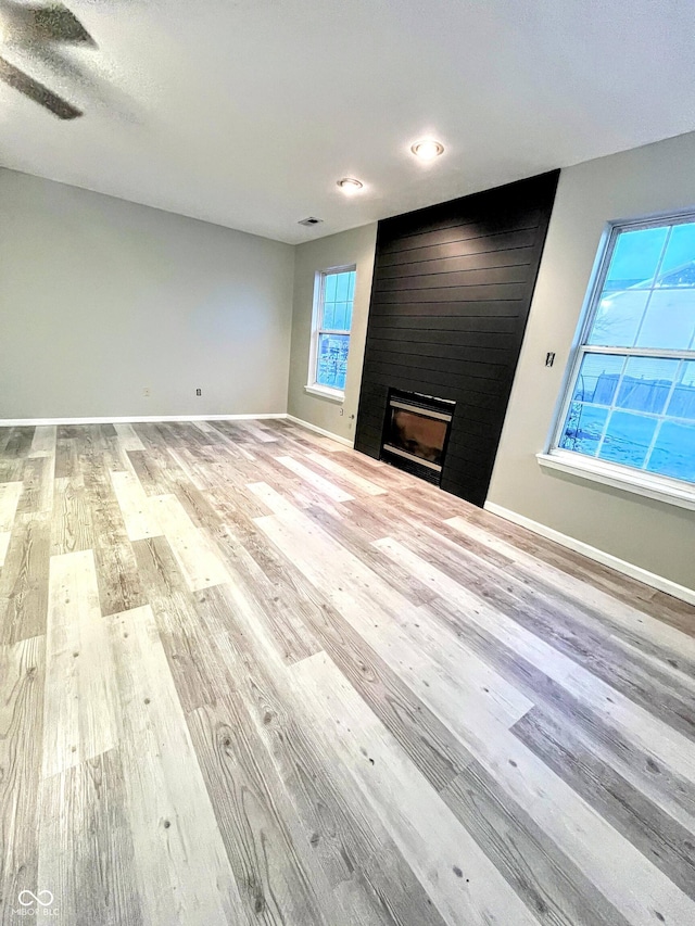 unfurnished living room with light hardwood / wood-style floors and a large fireplace