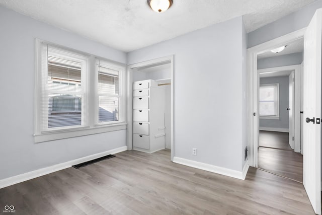 unfurnished bedroom with a textured ceiling, a closet, and light wood-type flooring