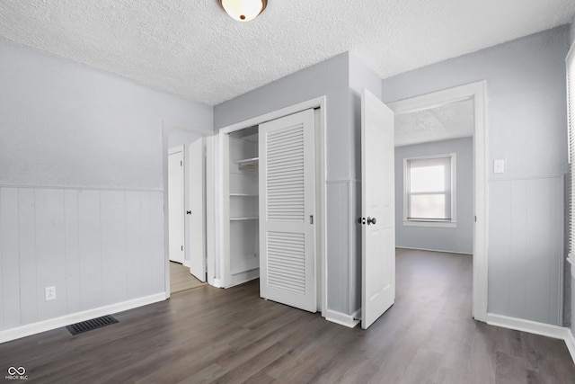 unfurnished bedroom with dark wood-type flooring, a textured ceiling, and a closet