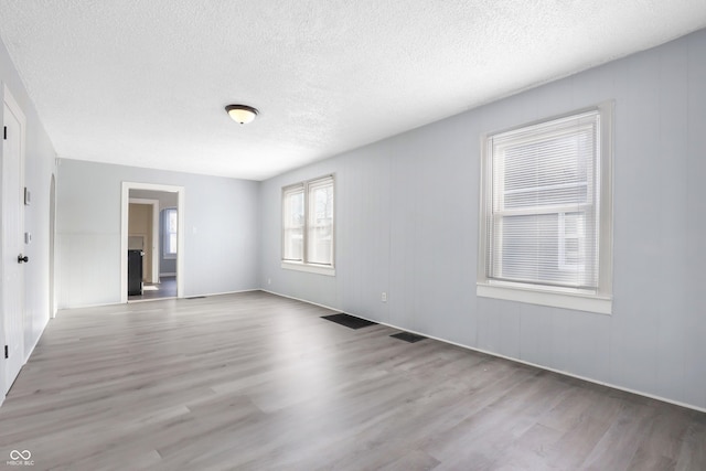 empty room with light hardwood / wood-style floors and a textured ceiling