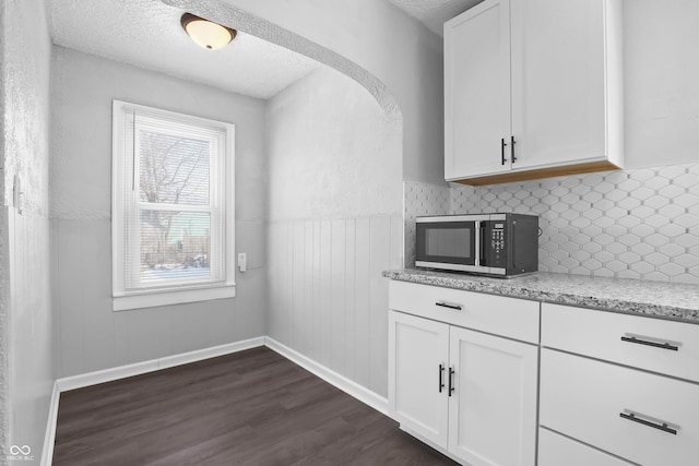 kitchen featuring light stone counters, dark hardwood / wood-style flooring, a textured ceiling, and white cabinets