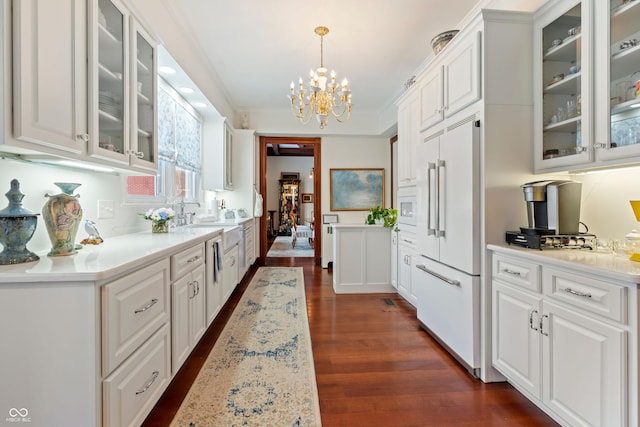 kitchen featuring white cabinetry, ornamental molding, dark hardwood / wood-style flooring, paneled built in fridge, and pendant lighting