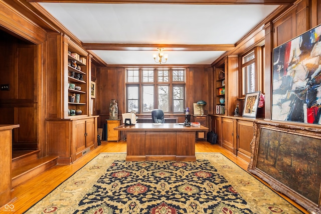 office space with built in shelves, a notable chandelier, light hardwood / wood-style floors, and wood walls