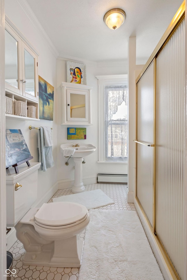 bathroom with a baseboard heating unit, crown molding, a shower with door, and toilet