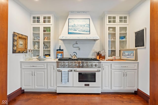 bar featuring premium range hood, range with two ovens, crown molding, decorative backsplash, and white cabinets