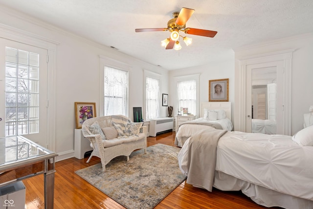 bedroom featuring radiator, wood-type flooring, ceiling fan, crown molding, and a textured ceiling