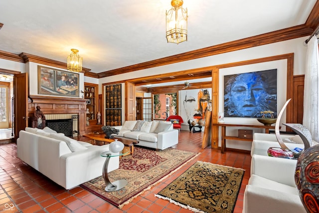 tiled living room featuring a notable chandelier, ornamental molding, and a brick fireplace