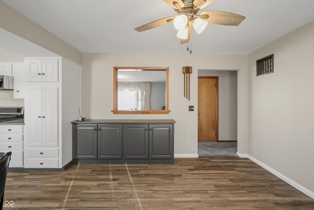 kitchen with stove, dark hardwood / wood-style floors, gray cabinetry, and ceiling fan