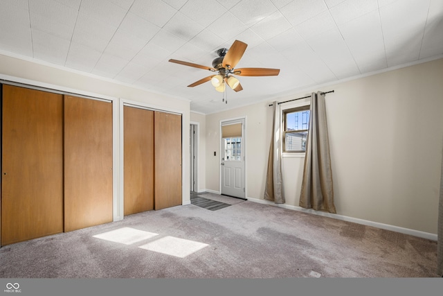 unfurnished bedroom with crown molding, two closets, light colored carpet, and ceiling fan