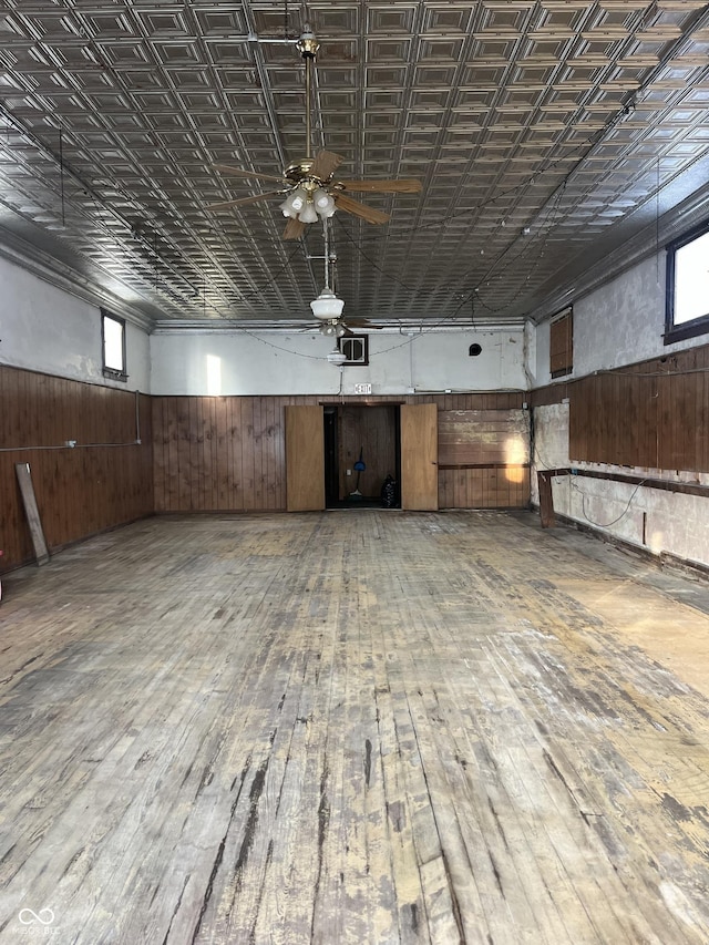 basement with hardwood / wood-style flooring, ceiling fan, and wood walls