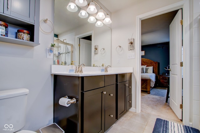 bathroom featuring tile patterned floors, toilet, a shower with door, and vanity