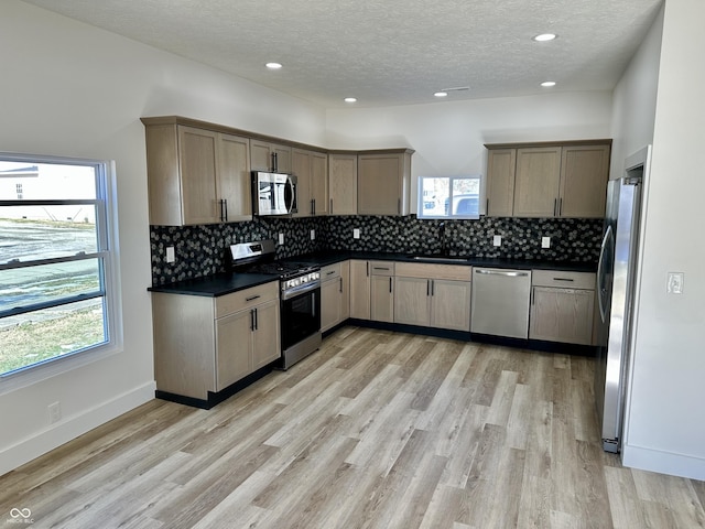 kitchen featuring stainless steel appliances, a textured ceiling, light wood-type flooring, and decorative backsplash