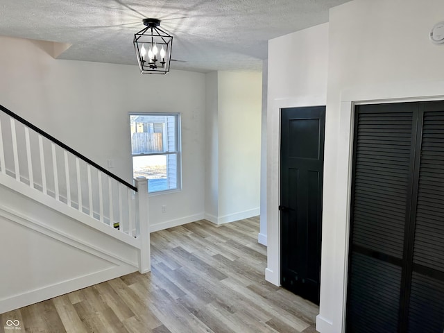 foyer with an inviting chandelier, a textured ceiling, and light hardwood / wood-style floors