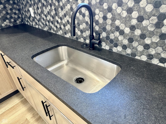 room details featuring sink, hardwood / wood-style floors, light brown cabinetry, and decorative backsplash