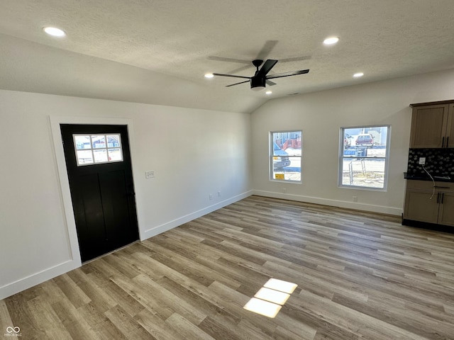 entrance foyer with vaulted ceiling, ceiling fan, a textured ceiling, and light hardwood / wood-style floors