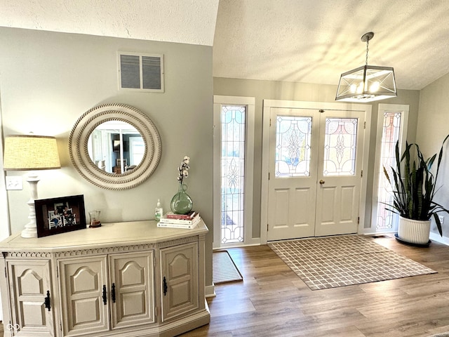 entryway with hardwood / wood-style floors, a notable chandelier, and a textured ceiling