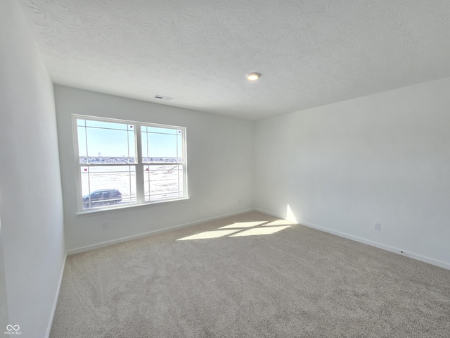 carpeted empty room featuring a textured ceiling