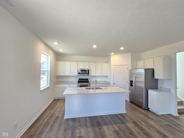 kitchen with visible vents, a center island with sink, light countertops, appliances with stainless steel finishes, and a sink