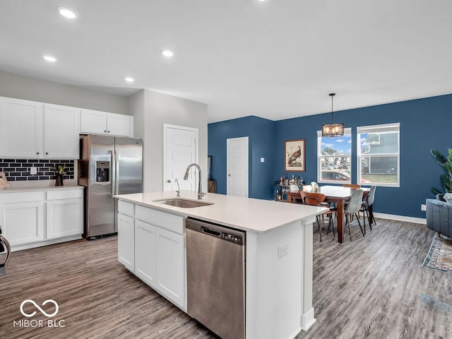 kitchen with stainless steel appliances, sink, white cabinets, and decorative light fixtures