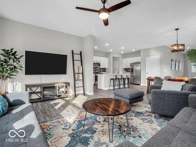 living room with ceiling fan, sink, and light wood-type flooring